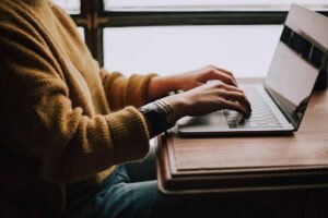 A professional typing on a laptop in a cozy workspace, using a professional services automation system to manage projects efficiently.